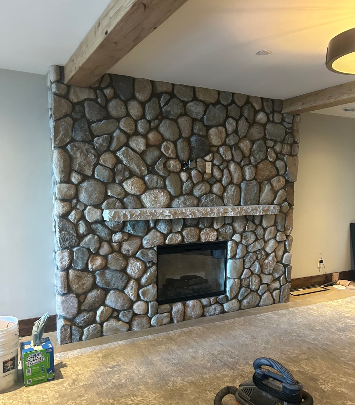 Picture of a fireplace surrounded by beautiful gray and beige medium size stones and stonework  